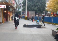 步行街一广告牌倒了  她路过时玩手机差点被绊倒